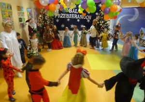 Grupa dzieci z panią dyrektor Marią Królikowską i panią Arletą tańczą w kole.